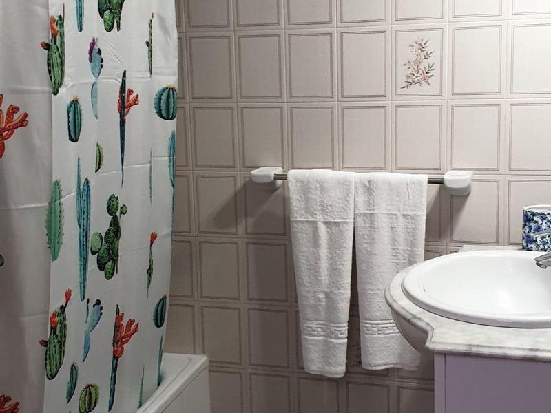 Ein Badezimmer mit Duschvorhang, Handtüchern und Waschbecken unter Holzbalken.