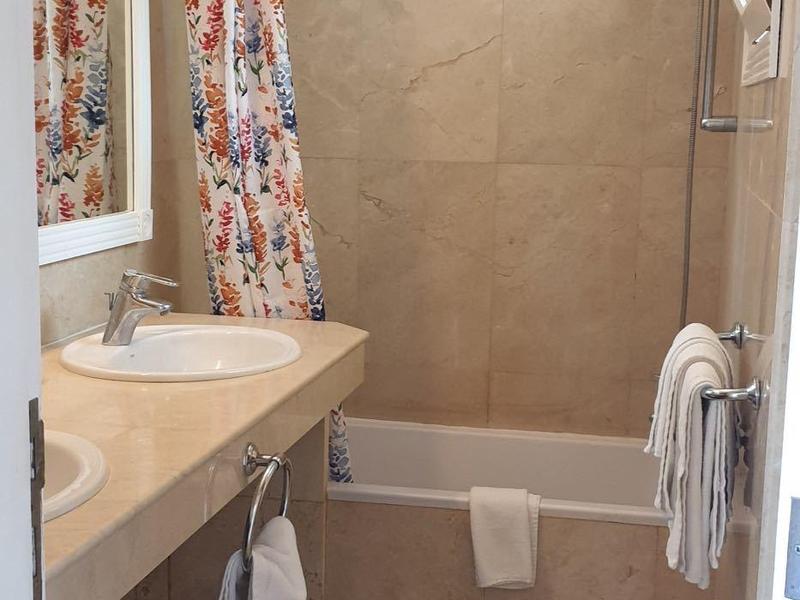 Sauberes Hotelbadezimmer mit Dusche, Waschbecken, Spiegel und Handtüchern.