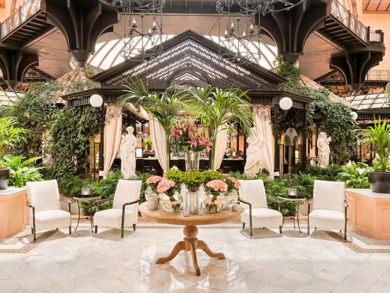 Elegantní vnitřní zahrada s bujnými rostlinami a posezením v hotelové hale.