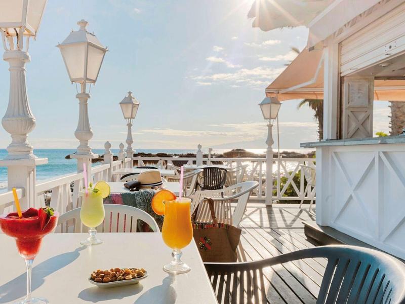 Venkovní plážový bar s barevnými koktejly a slunným výhledem na oceán