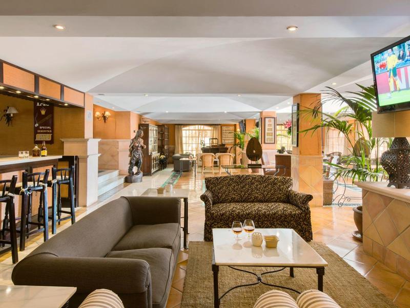 Moderní hotelová hala s pohodlným posezením, barem a teplým osvětlením.