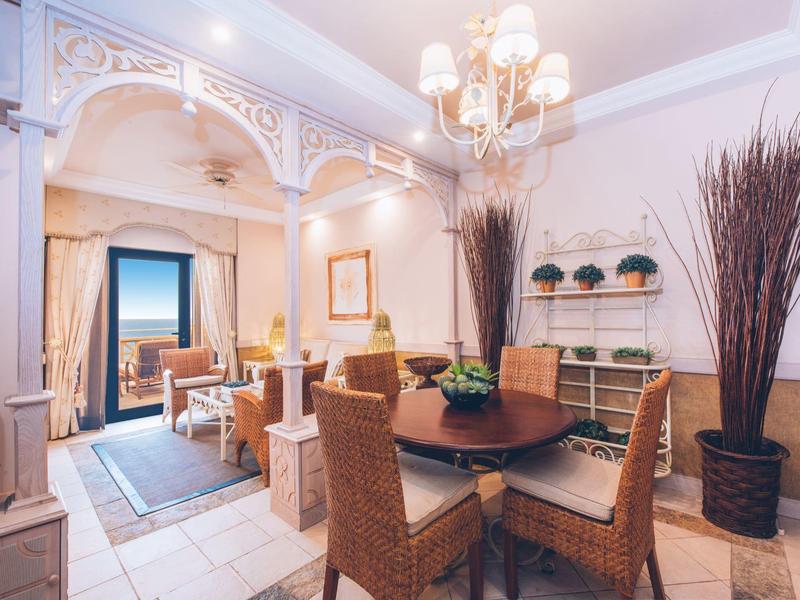 Gemütlicher Essbereich mit rundem Holztisch, Stühlen aus Korbgeflecht und dekorativen Pflanzen.