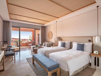 Moderne hotelkamer met twee eenpersoonsbedden, balkon en uitzicht op de stad.