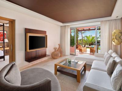 Moderner Wohnraum mit großen Fenstern, hellen Sofas, Holzdecke und Blick auf Terrasse mit Pflanzen.