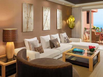 Gemütliches Wohnzimmer mit weißem Sofa, Holztischen, brauner Lampe und Meeresblick.
