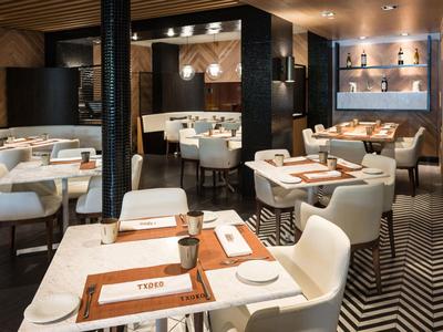 Modernes Restaurant mit weißen Stühlen, Holztischen und warmem, stimmungsvollem Licht.
