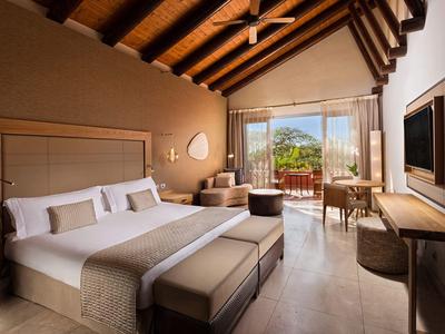 Gemütliches Schlafzimmer mit Holzdecke, großem Bett, Balkon und Blick auf grüne Landschaft.