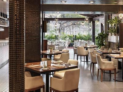 Modernes Restaurant mit Holztischen, beigen Stühlen und großem Fenster zu grüner Außen area.