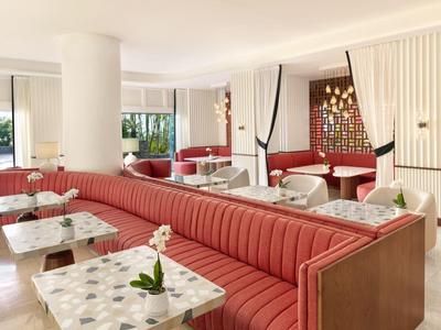 Helles, modernes Restaurant mit roten Sitzbänken, weißen Tischen und großen Fenstern zum Außenbereich.
