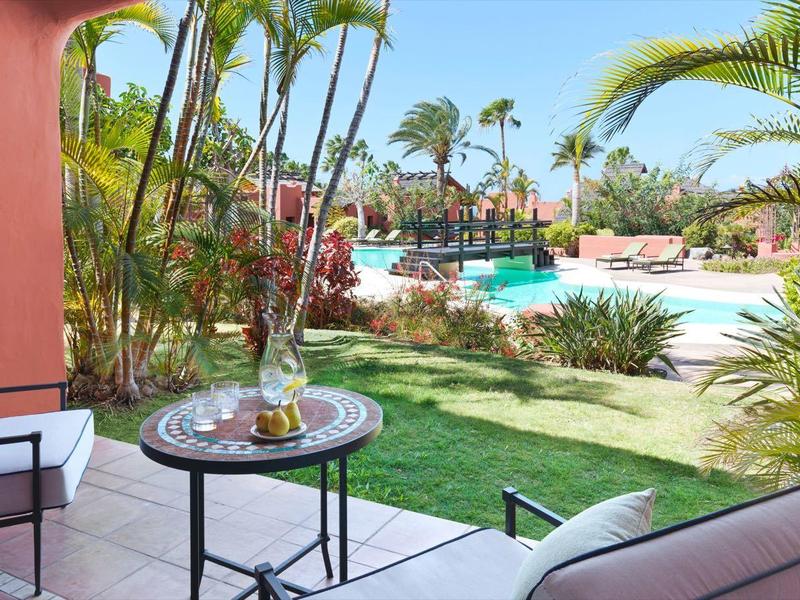 Gezellig terras met zithoek met uitzicht op zwembad en tropische planten.