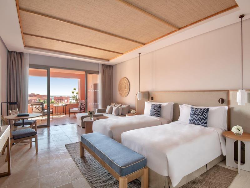 Moderne hotelkamer met twee eenpersoonsbedden, balkon en uitzicht op de stad.