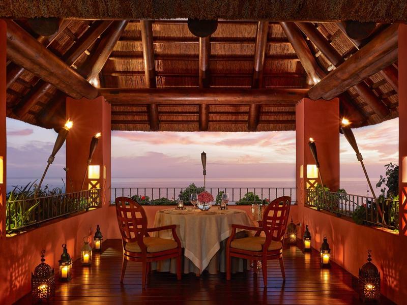 Romantische met kaarslicht gedekte tafel onder houten dak bij zonsondergang