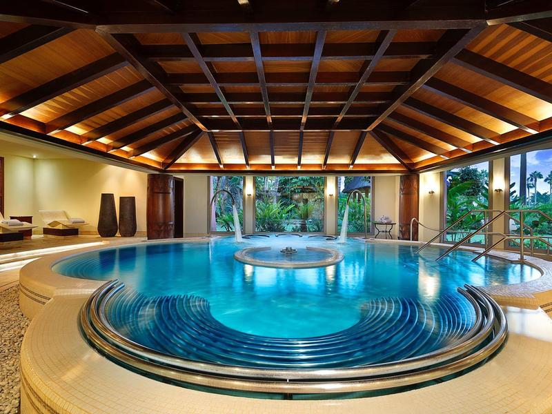 Luxe binnenzwembad met bubbelbad in een open, met hout beklede hal.