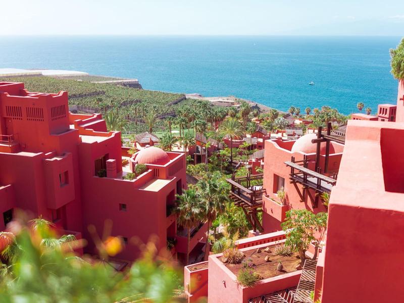 Rode gebouwen met zeezicht en groene begroeiing op de achtergrond