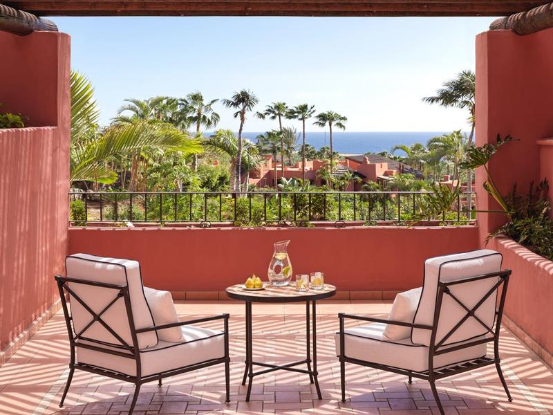 Gezellig terras met twee stoelen en tafel met uitzicht op tropische tuin en zee.