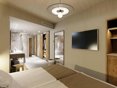 Modern hotel room interior with double bed, TV, and open wardrobe.