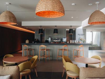 Modern, stylish hotel lounge area with bar, wooden tables, and comfortable chairs.