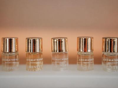 Five small bottles with golden caps lined up on a white surface.