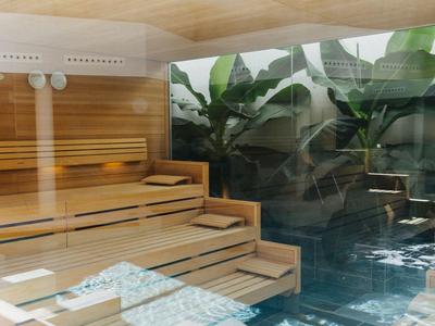 Interior of a wooden sauna with a view of a pool and greenery.