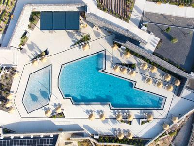 Luftaufnahme von einem Hotelpool mit Sonnenschirmen und Liegestühlen auf der Terrasse.