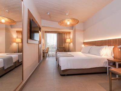Modern hotel room with double bed, mirrored wall, and desk by the window.