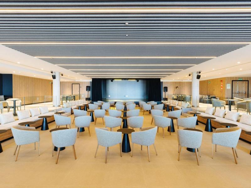 Large modern event hall with rows of chairs and stage area at the end.