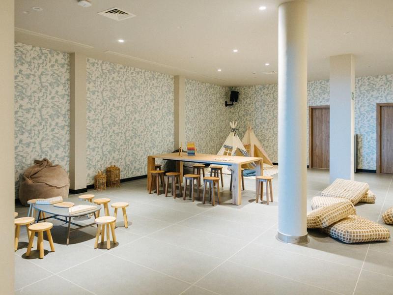 Modern lounge area with tables, cushions, and stools in neutral tones.