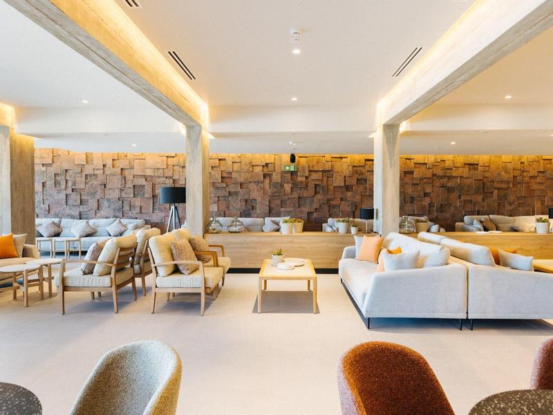 Bright, modern lounge with comfortable white sofas and decorative wall design.