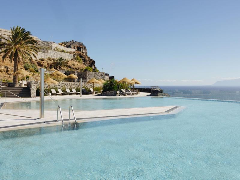 Infinity pool overlooking the sea and rocky cliffs under clear sky
