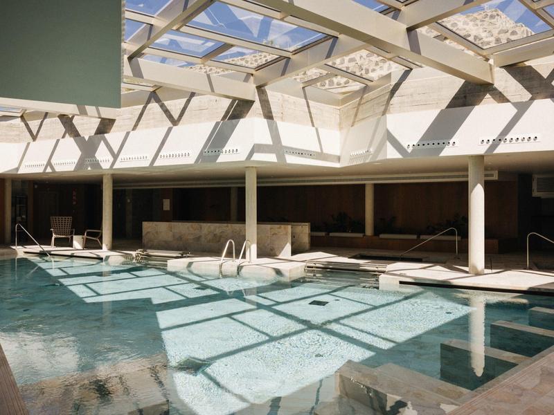Indoor pool with clear water and abundant natural light from large glass ceiling.