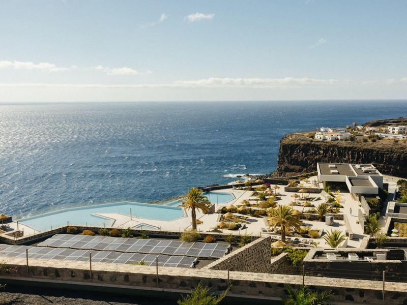 Luxurious hotel with infinity pool overlooking the vast sea on a cliff.
