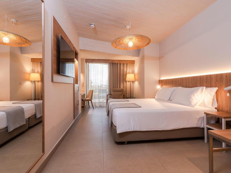 Modern hotel room with double bed, mirrored wall, and desk by the window.