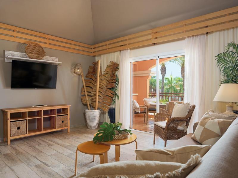 Gemütliches Wohnzimmer mit hellen Holzmöbeln, Pflanzen und Zugang zu einer Terrasse mit Stühlen.