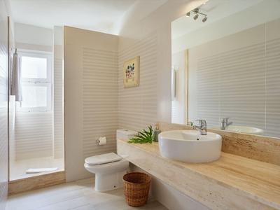 Bagno d'hotel luminoso con lavandino moderno e doccia a passo.