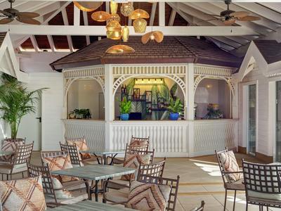 Luminoso ristorante dell'hotel con tavoli rotondi, sedie in metallo e padiglione in legno decorativo.