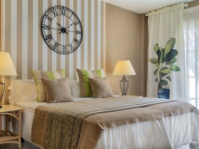 Camera d'hotel accogliente con letto grande, parete a righe e grandi finestre.