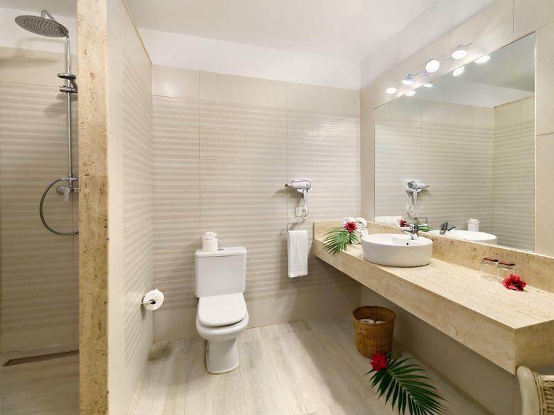 Modernes Badezimmer mit Toilette, Waschbecken, großem Spiegel und begehbarer Dusche in hellen Farben.