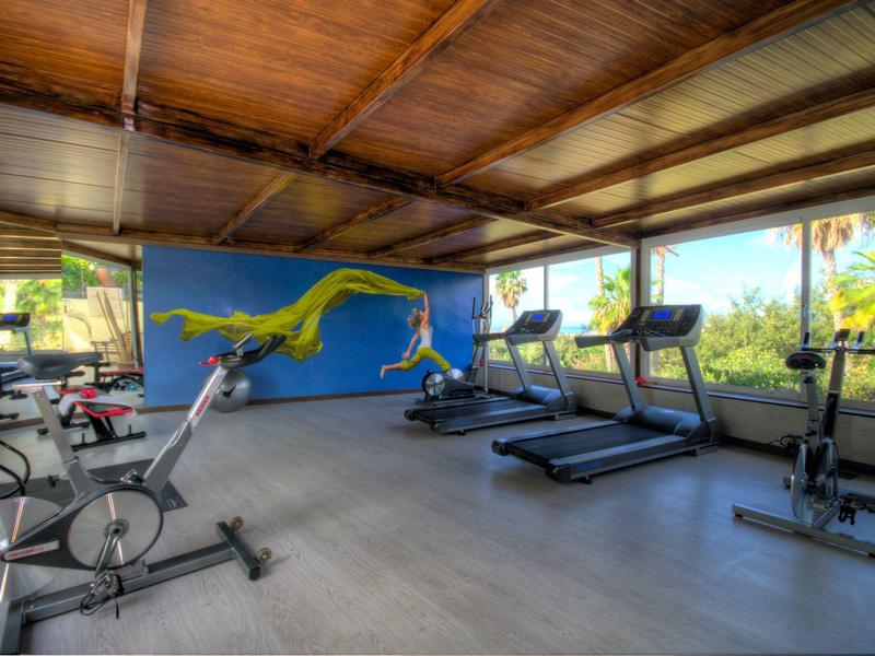 Fitnessraum mit Geräten wie Fahrrädern, Laufbändern und Rudergeräten, helle Räume mit Holzdecke.