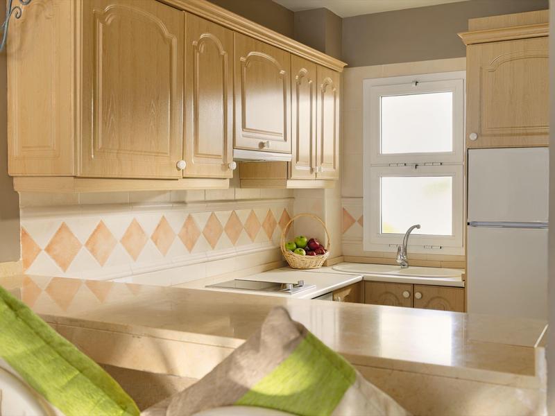 Moderne helle Küche mit Holzschränken, Fliesenrückwand, Fenster und Obstschale auf der Arbeitsplatte.