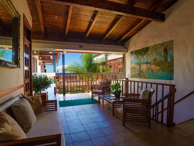 Terrasse couverte avec banc en bois donnant sur une piscine et un jardin.