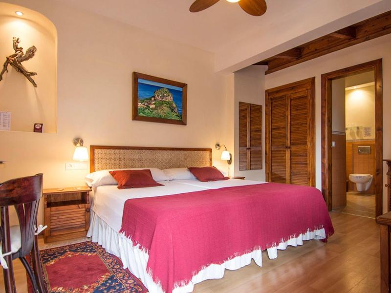 Chambre d'hôtel confortable avec lit double, meubles en bois et accès à la salle de bain.