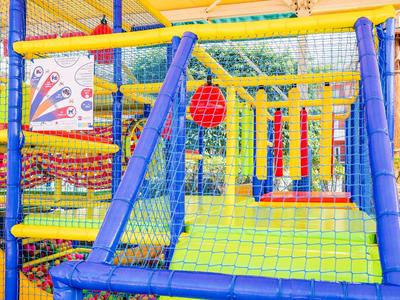 Buntes Spielgerüst mit Netzen, Kletternetzen und Hängeelementen im Außenbereich.