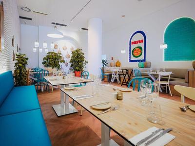 Modern, licht restaurant met blauwe banken en houten tafels.