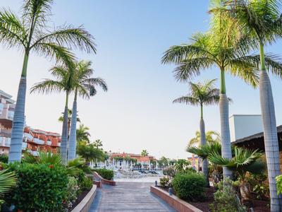 Hotel met zwembad en palmbomen in een tropische omgeving onder een heldere hemel.