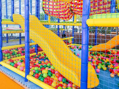Kleurrijke indoor speeltuin met gele glijbaan en gekleurde ballen in een hotel.