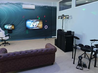 Gezellige gamekamer met bank, game-stoelen en aan de muur gemonteerde schermen.