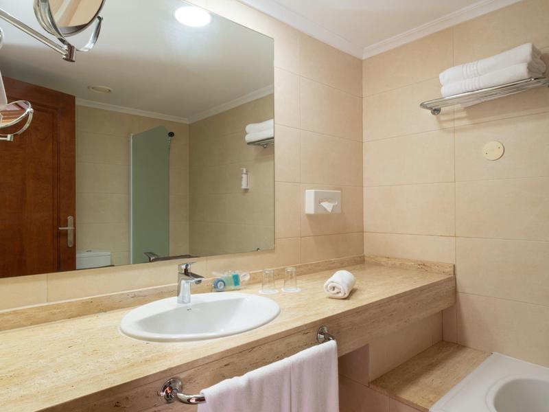 Helles Badezimmer mit großem Spiegel, Waschbecken und Badewanne.