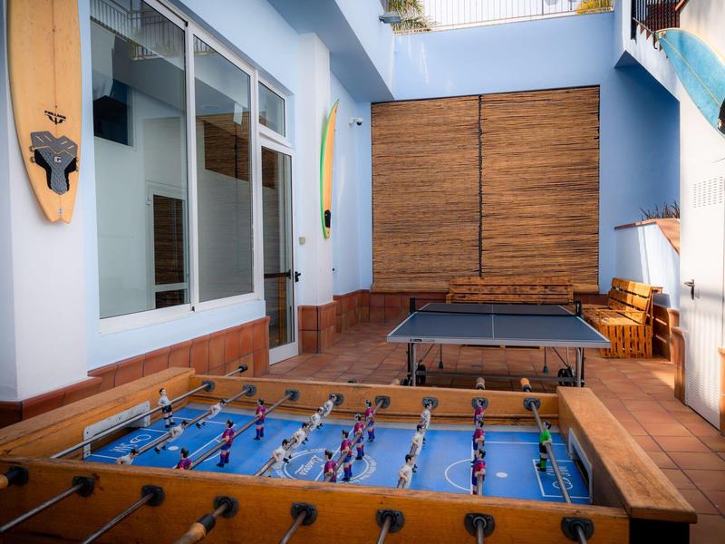 Ein Spielraum mit einem Tischfußballspiel und einem Tischtennistisch auf einer Terrasse mit blauen Wänden.