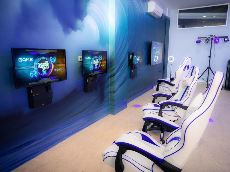 Drei weiße Gaming-Stühle vor Bildschirmen in einem modernen Raum mit blauem Ambiente.