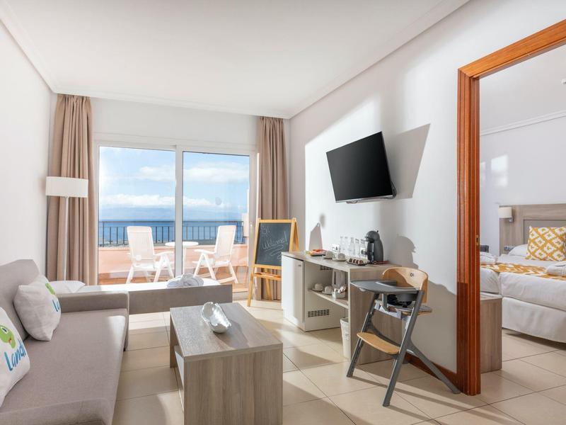 Helles Hotelzimmer mit Wohnzimmer, Balkon und Blick aufs Meer.
